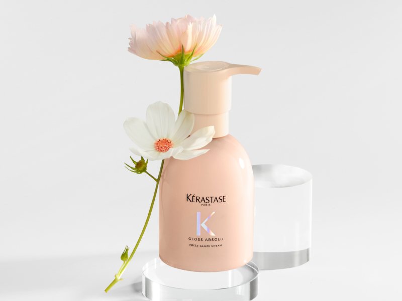 Frizz Glaze Cream de Kerastase rodeada de flores decorativas